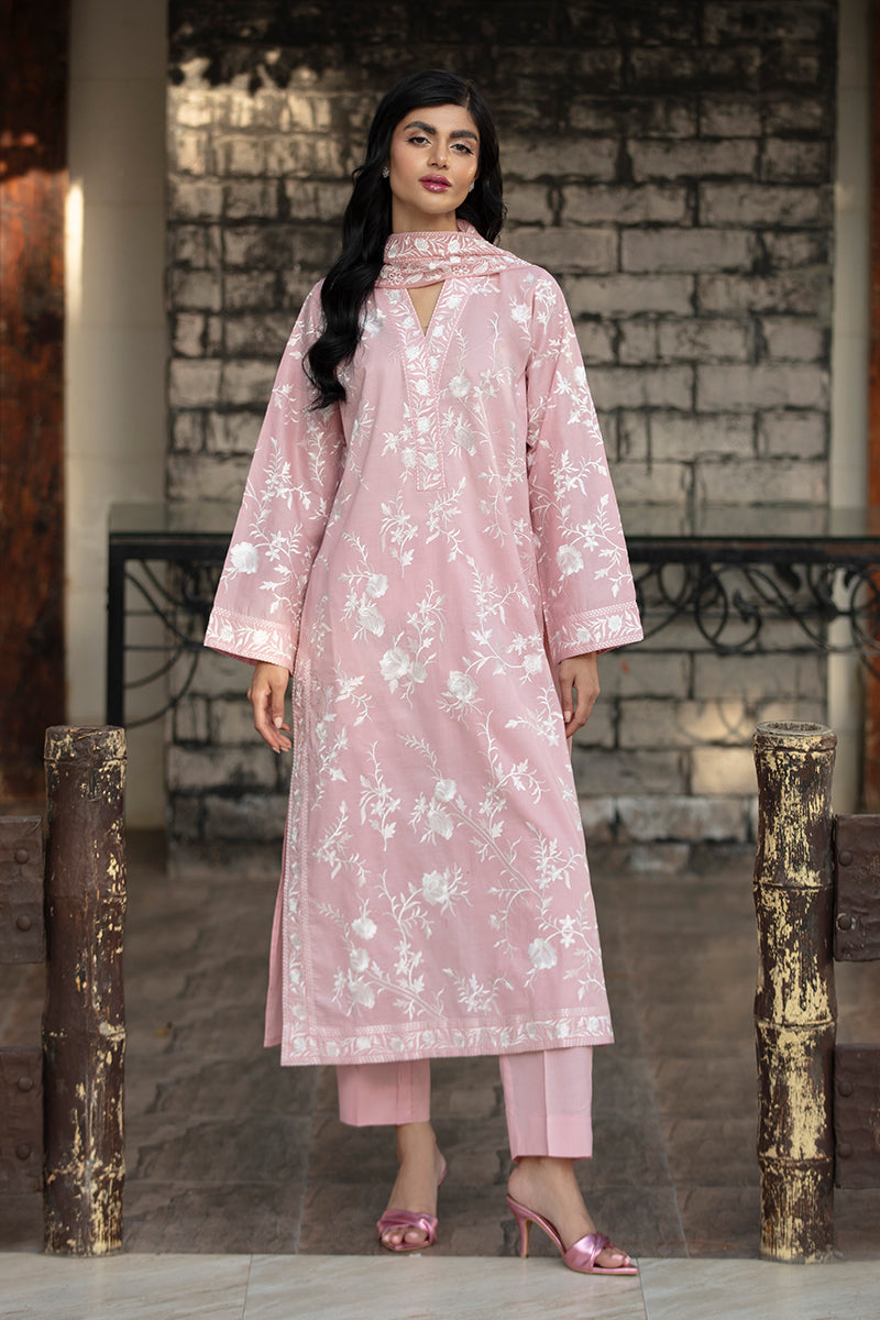 Woman wearing a pink floral dress standing against a stone wall.